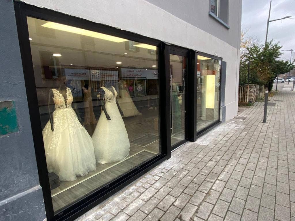 Devanture de magasin en aluminium noir avec vitrines et porte coulissante, réalisée par REM Fermetures