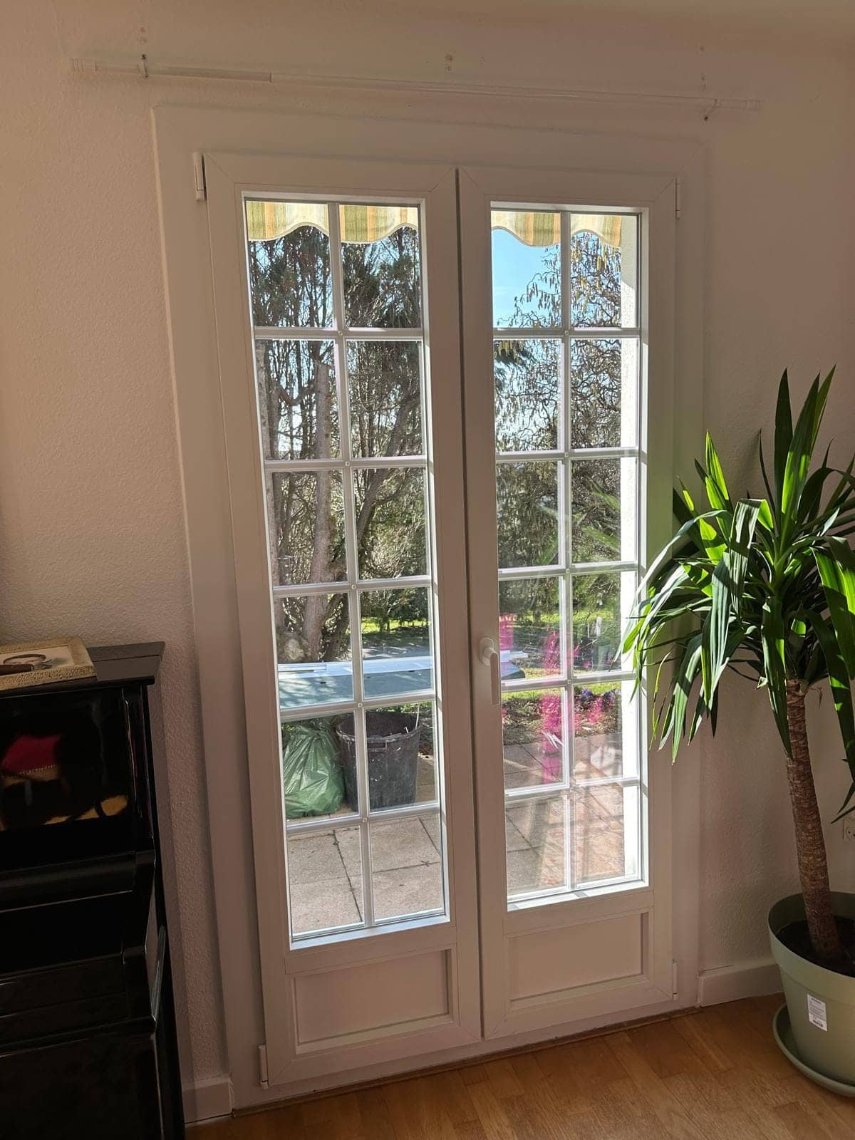 Porte-fenêtre PVC blanche à petits-bois dans un séjour ouvrant sur le jardin, posée par REM Fermetures