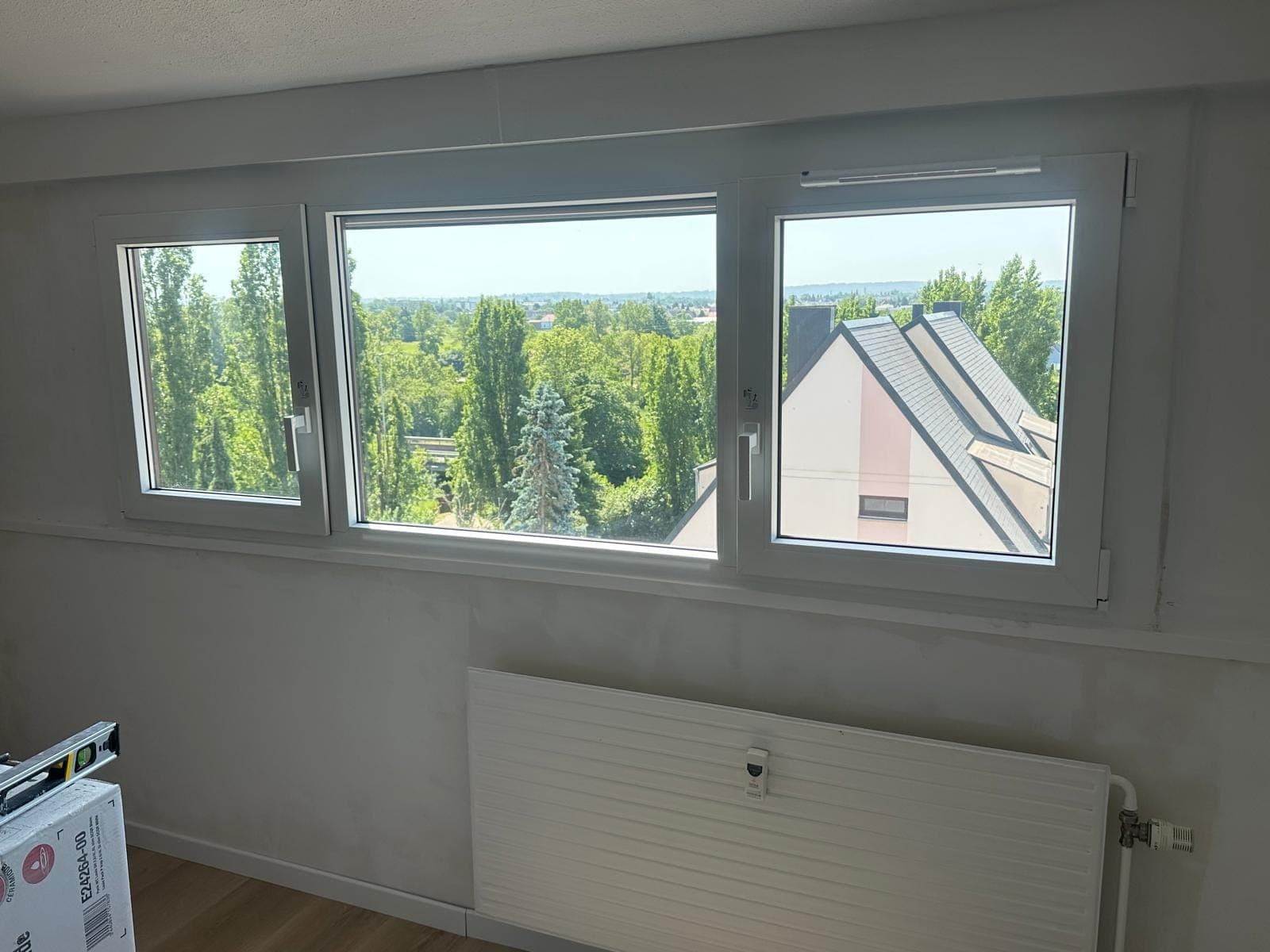 Fenêtre PVC à trois vantaux ouvrant sur une vue dégagée des hauteurs, posée par REM Fermetures