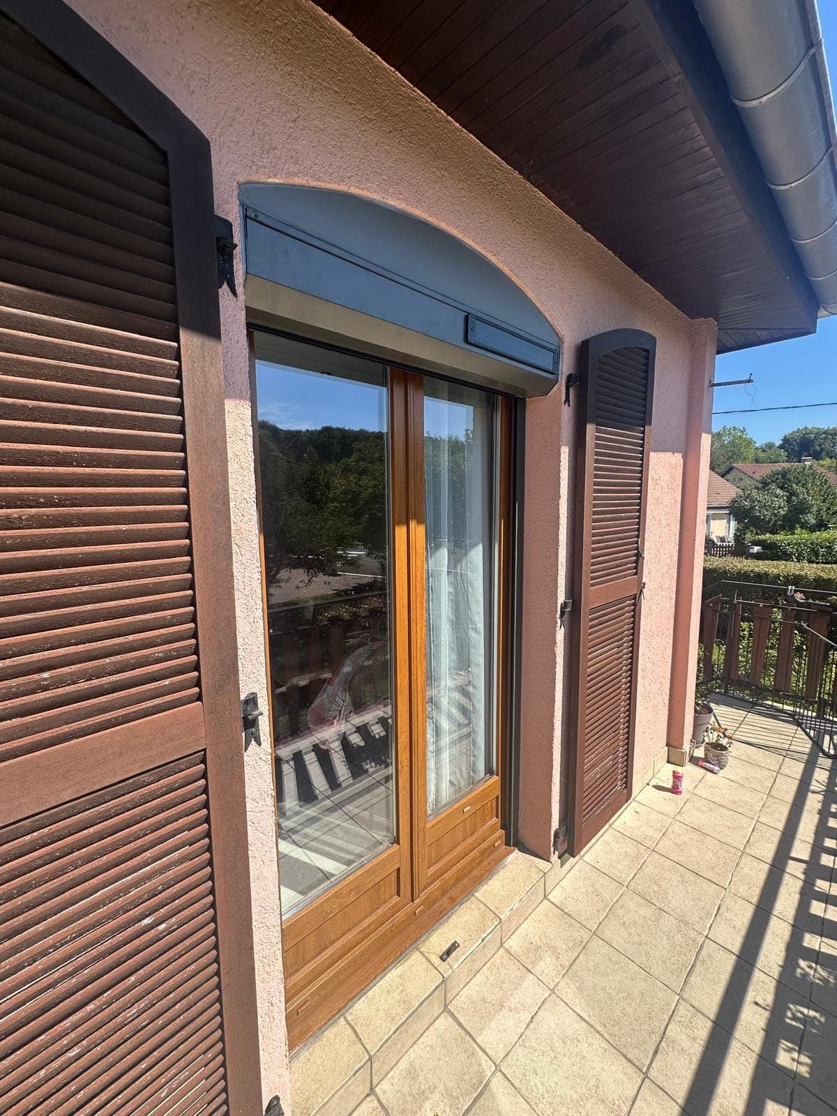 Porte-fenêtre coulissante en bois donnant sur une terrasse, posée par REM Fermetures