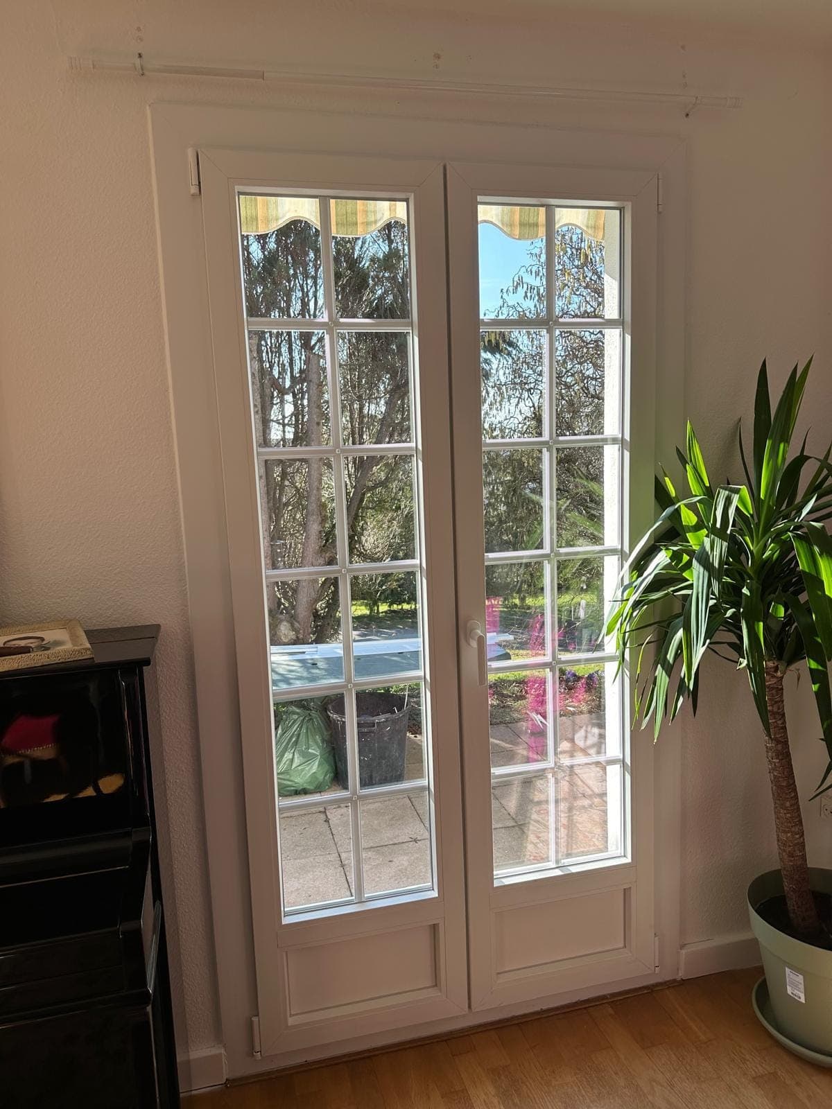 Porte-fenêtre PVC blanche à petits-bois dans un séjour ouvrant sur le jardin, posée par REM Fermetures